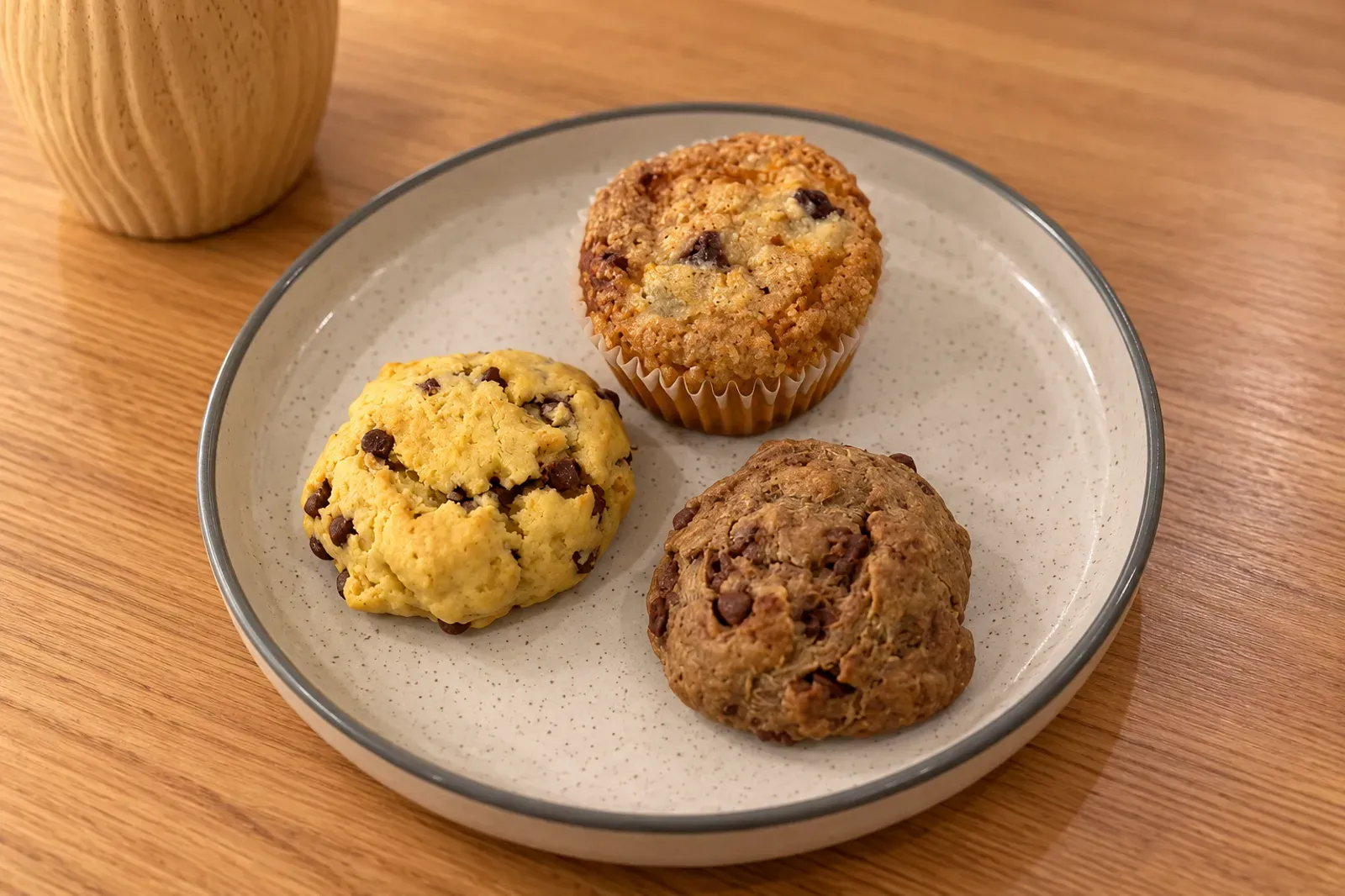 Muffin y dos cookies de chips de chocolate en plato de gres moteado